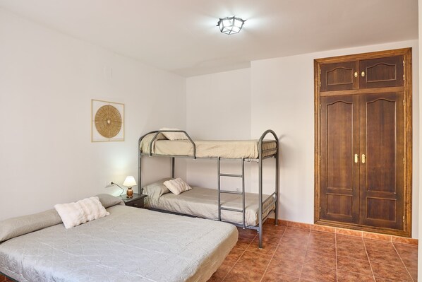 Una habitación con literas, un armario de madera, una lámpara fijada a la pared y un cuadro enmarcado.