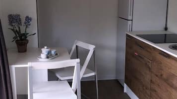 A compact kitchenette with a microwave, refrigerator, and a small dining area with a table and chairs.