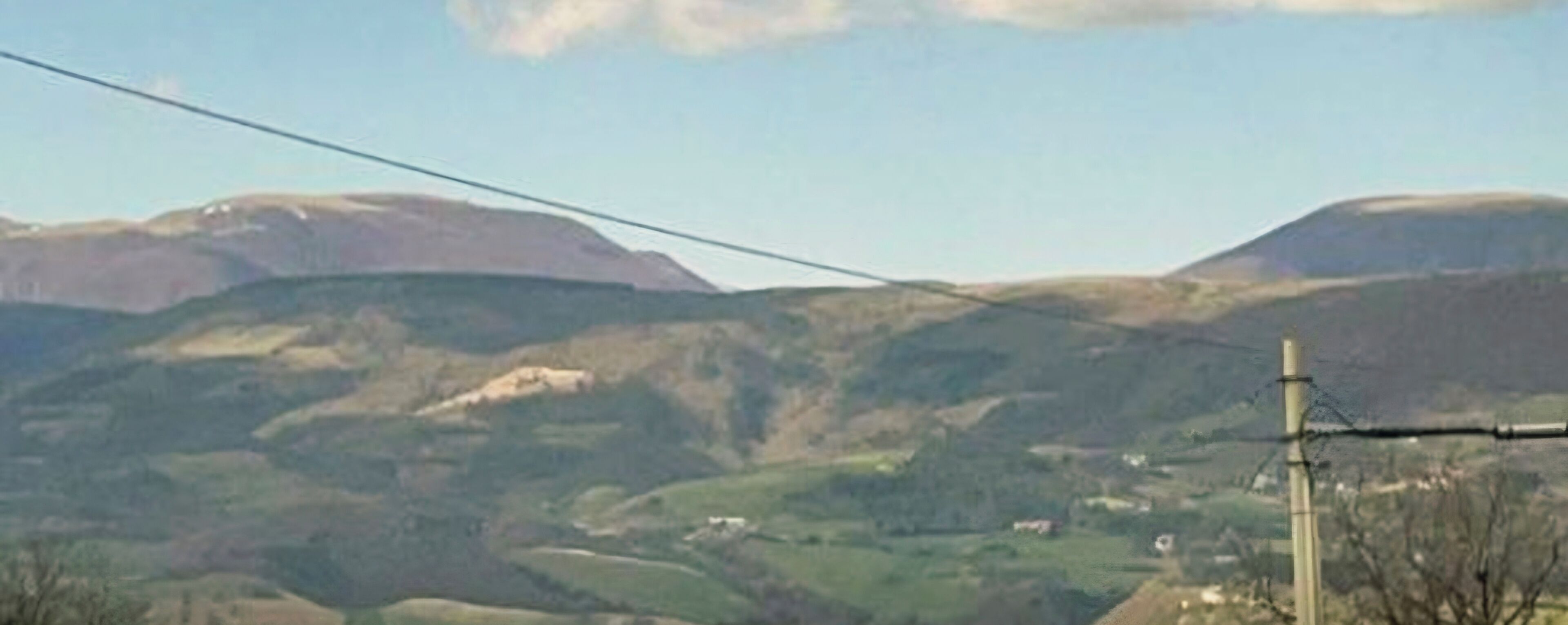 Un paysage rural caractérisé par des collines douces et un ciel dégagé.