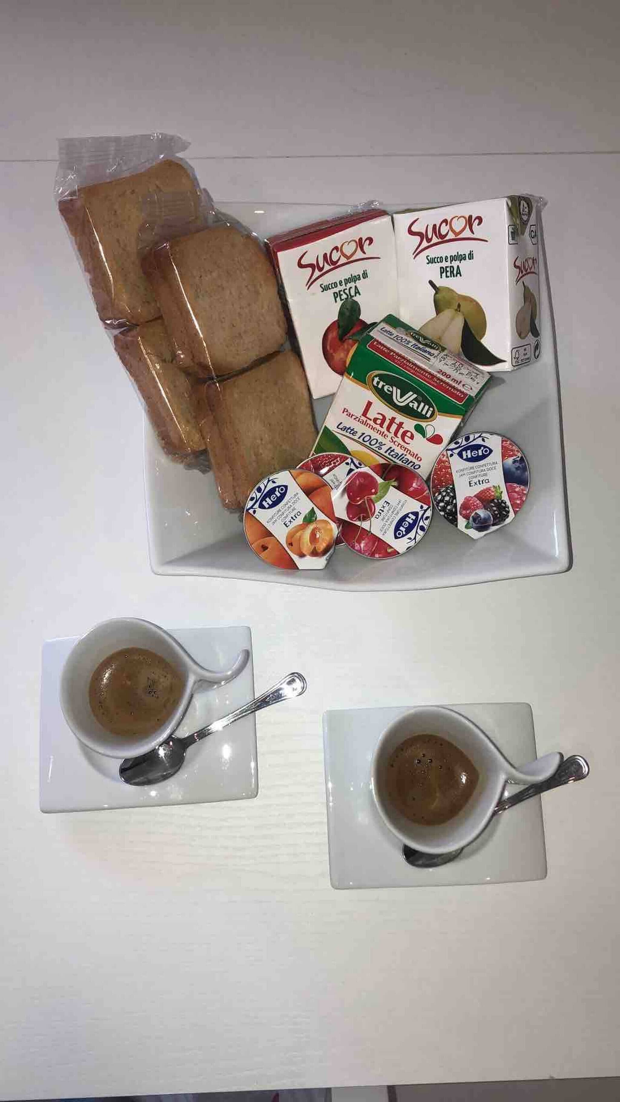 A breakfast tray with bread, Succor, TreValli, Hero, and two cups of coffee.