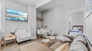 Un salon moderne comprenant un téléviseur à écran plat, un canapé, une table à manger avec des chaises et une petite table basse.