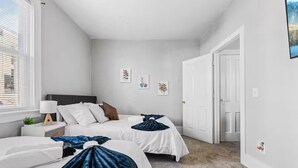 Une chambre avec deux lits, une table de chevet avec une lampe et une fenêtre avec des stores.