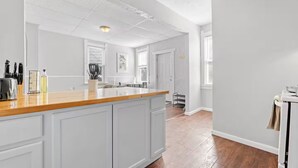 A kitchen with a wooden countertop, white cabinets, and a view to the dining area. - Cute Apt · Little Italy · Fast Wifi · Cozy Bed (Cleveland)