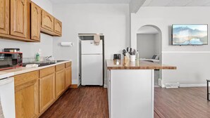 A modern kitchen with wooden cabinets, a microwave, a refrigerator, and a sink. - Cute Apt · Little Italy · Fast Wifi · Cozy Bed (Cleveland)