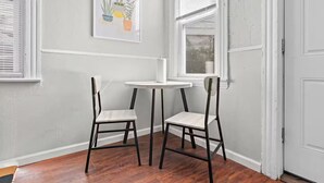 A corner room with two chairs and a small table, white walls, and a window with blinds. - Cute Apt · Little Italy · Fast Wifi · Cozy Bed (Cleveland)