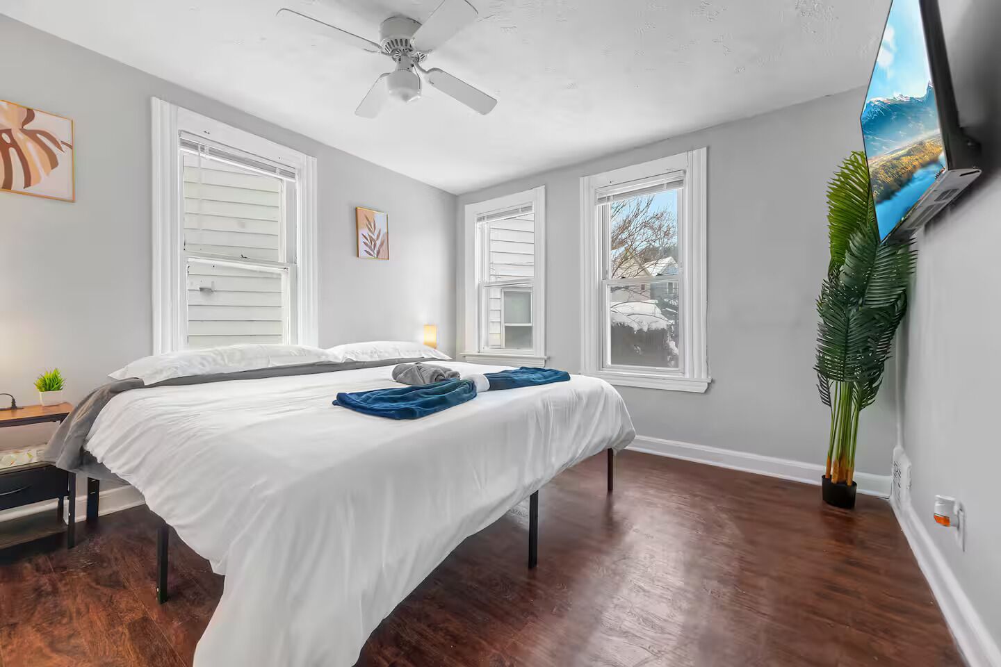 A bedroom with a bed, a ceiling fan, and a large window.