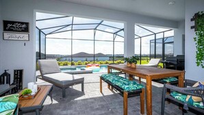 Un patio moderno al aire libre con cerramiento de vidrio, mobiliario y una piscina.