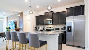 Una cocina moderna con armarios oscuros, electrodomésticos de acero inoxidable y una isla central con taburetes de bar.