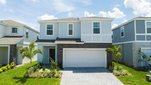 A modern two-story house with a garage, a stone facade, and a well-maintained lawn. - Luxury Disney Villa / 7BR with Themed Rooms & Private Pool in Windsor Island (Davenport)