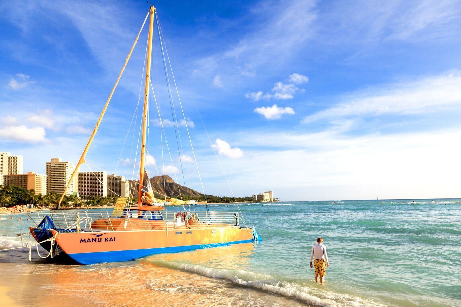 A beach with a boat named "MANU KAI" docked near the shore.