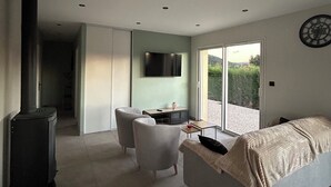 Uma sala de estar moderna com sofá, televisão, lareira e área de jantar com mesa e cadeiras.
