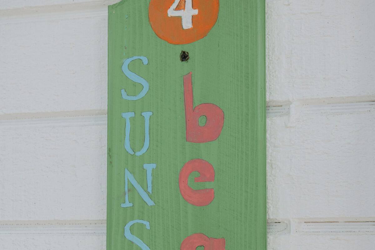A vertical sign with the words "4 beach" and "sunset" on a green background.