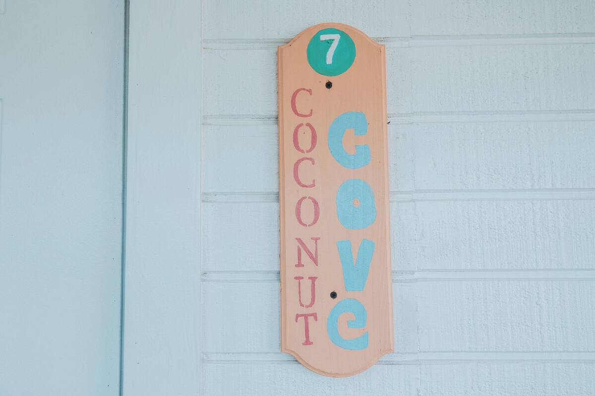 A wooden sign with the number 7 and the words "Coconut Cove" on a light blue wall.