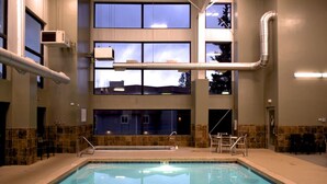 An indoor swimming pool with clear glass walls, a tiled floor, and a seating area with chairs. - Winter Park Condo w/ Fireplace, Centrally Located (Winter Park)