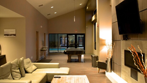 A modern living room with a pool table, comfortable seating, a fireplace, and a TV. - Winter Park Condo w/ Fireplace, Centrally Located (Winter Park)