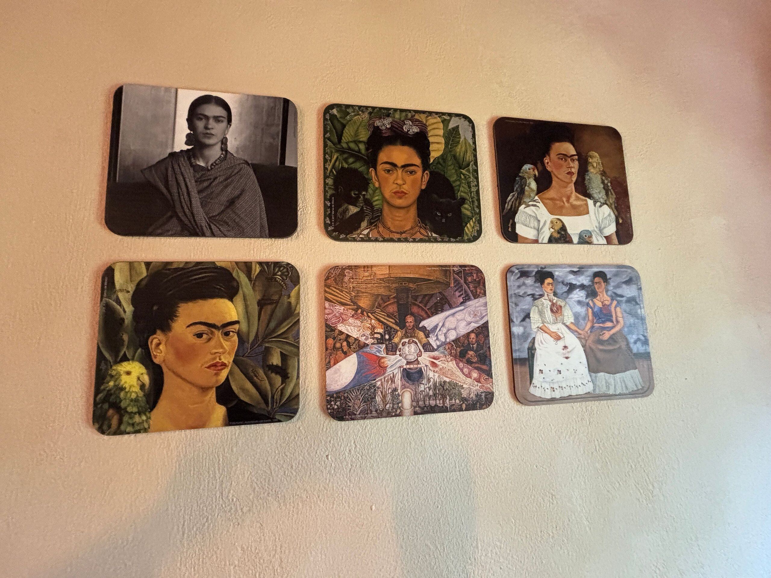Six vintage-style playing cards with portraits and botanical designs, arranged on a wall.