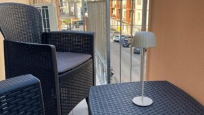 A balcony with wicker furniture, a table, and a lamp.