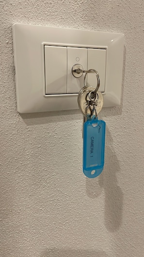 Een sleutelhanger met een blauw label dat hangt aan een sleutel, bevestigd aan een wit stopcontact.