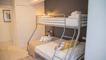 A bunk bed room with a small bedside table, a wall-mounted lamp, and a framed picture on the wall.