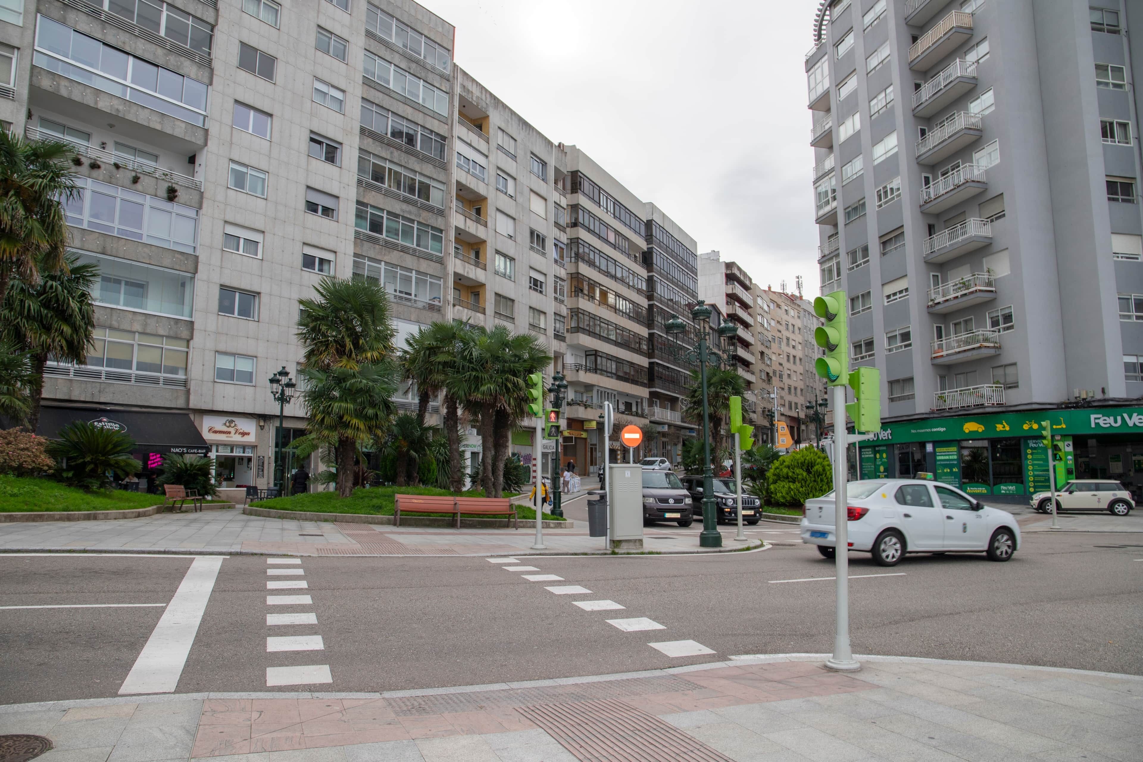 A multi-story residential building with balconies, a pedestrian crossing, and a street with cars and a traffic light.