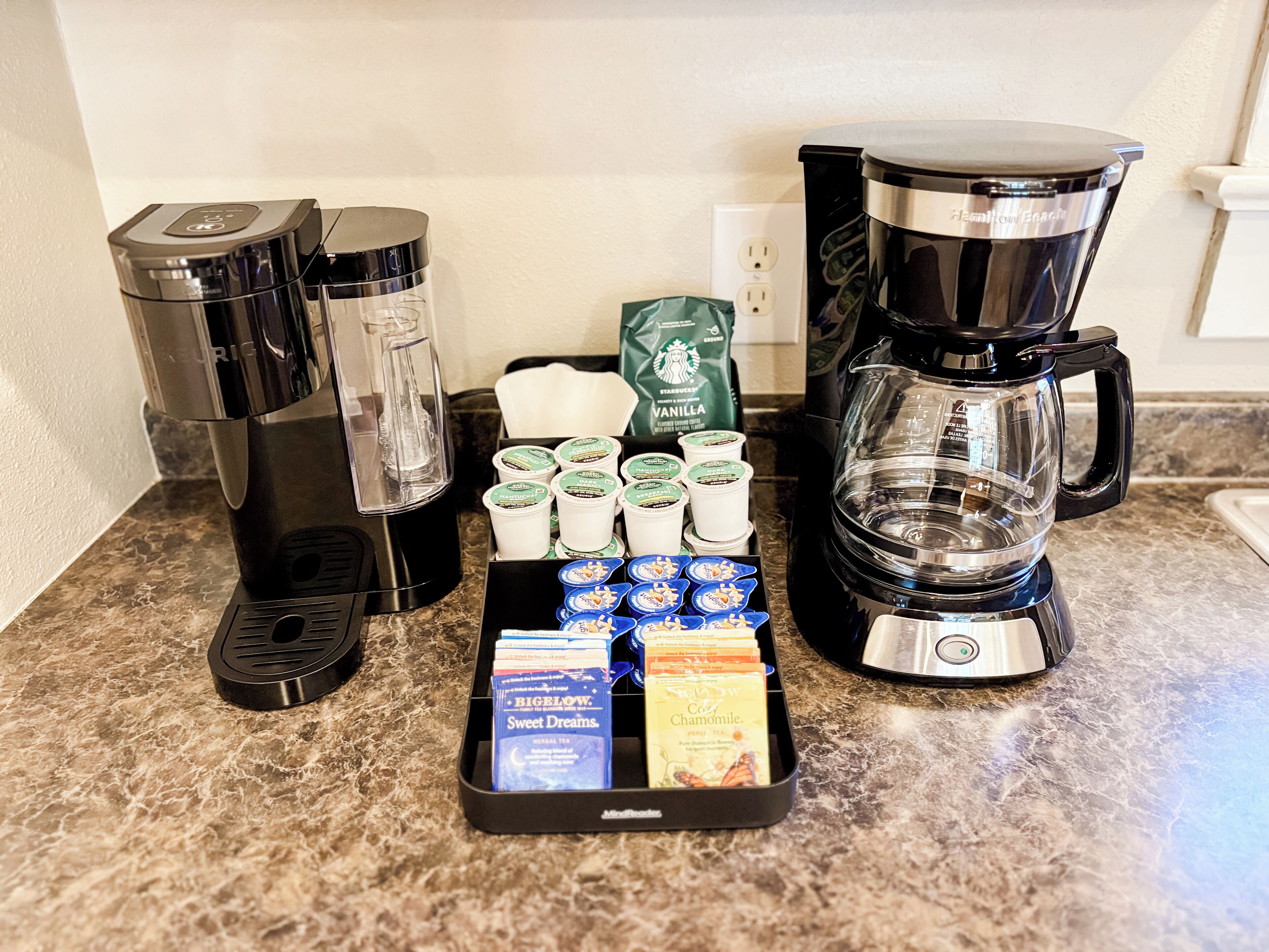A coffee station with multiple coffee makers and a variety of coffee pods.