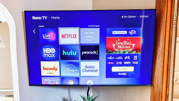 Una TV a schermo piatto montata a parete sopra un mobile in legno con un camino sottostante.