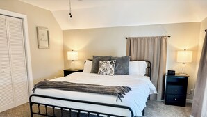 Una camera da letto con un letto, due comodini con lampade, un tavolino, un quadro incorniciato e un armadio con ante scorrevoli.