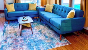 Un soggiorno con un divano ad angolo blu, un tavolino da caffè e un tappeto decorato.