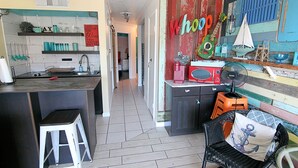Et køkken med en bar, et spiseområde med en fletstol, og en væg med et 'Whoop' skilt.