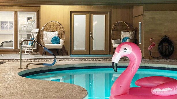 A swimming pool with a pink flamingo float, a chair with a blue pillow, and a door with a frosted glass panel. - Pet-friendly 4-bedroom + Pool (Richardson)