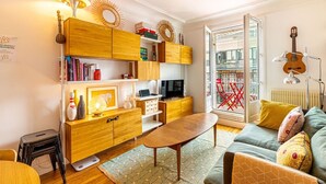 Een moderne woonkamer met houten meubels, een televisie en een gitaar.