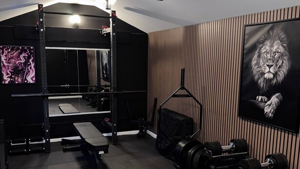 Een sportschool met een squats rek, bank en gewichtrekken.