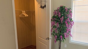 Een kamer met een houten kast, een potplant met roze bloemen en een kamerbreed tapijt met dessin.