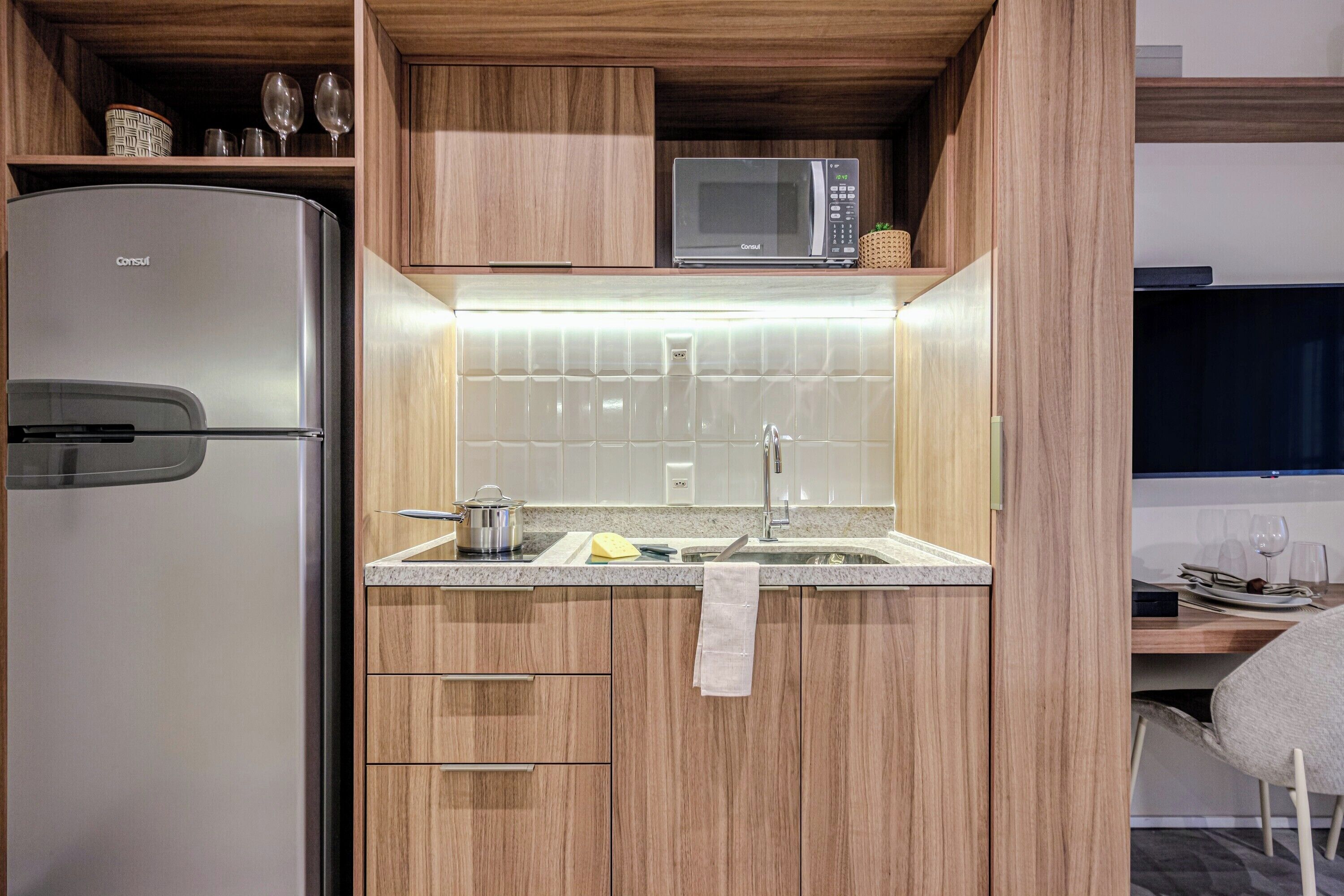 A compact kitchen with a refrigerator, microwave, and wooden cabinets.