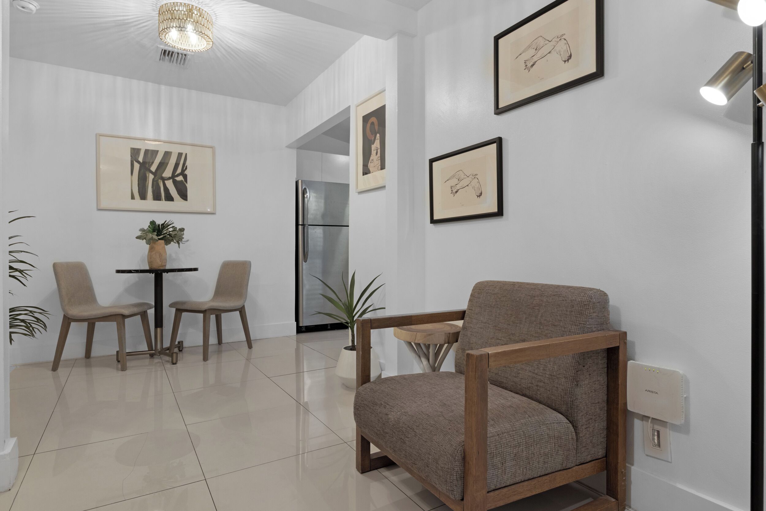 Una sala de estar moderna con un sillón de madera, una mesita con sillas y cuadros en las paredes.
