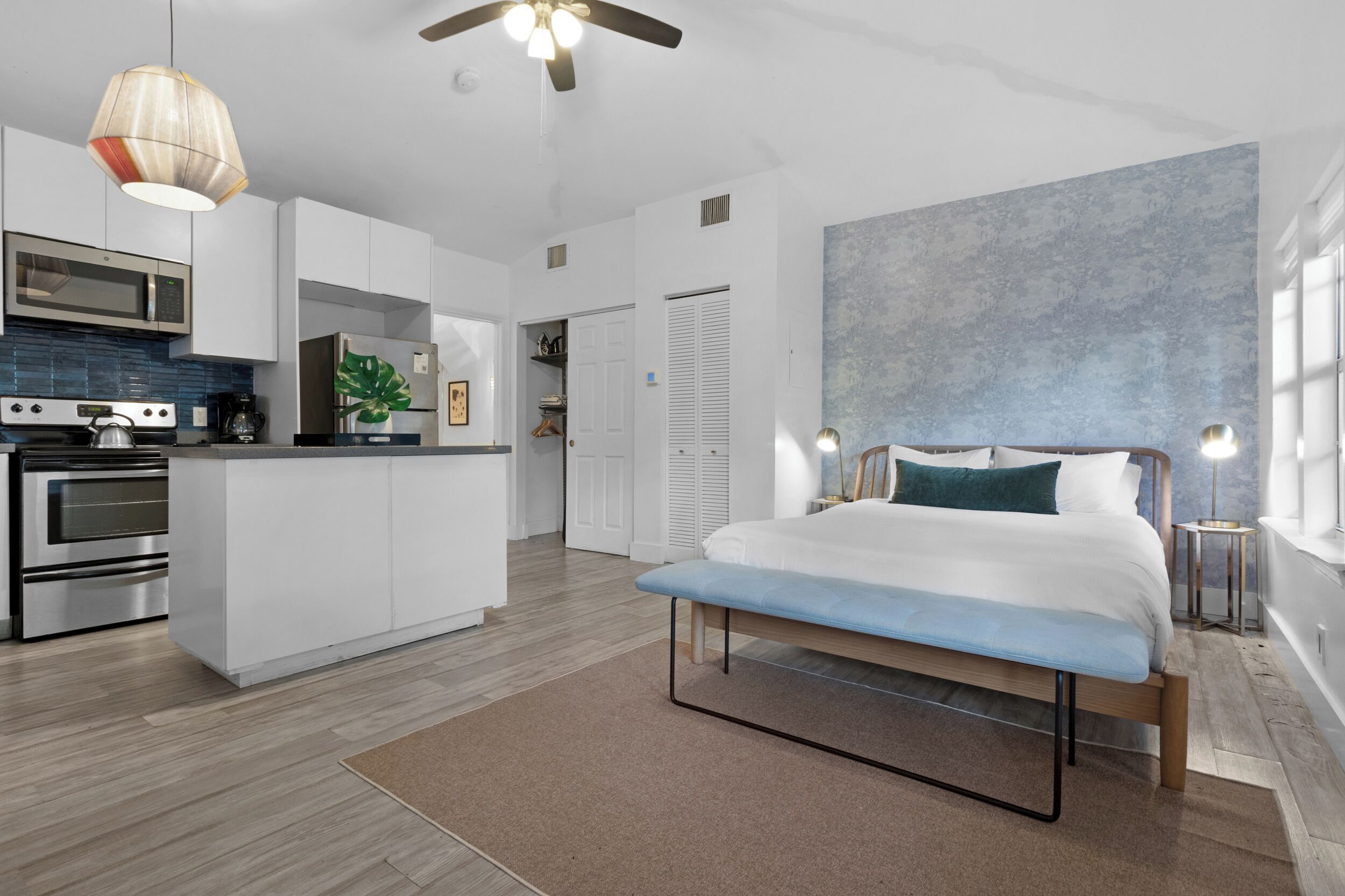 Un dormitorio moderno con una cama grande, mesitas de noche y vistas al área de la cocina.