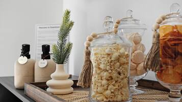 A wooden tray with glass jars containing popcorn and other snacks, a small potted plant, and two bottles labeled "SPICE" and "ALOE."