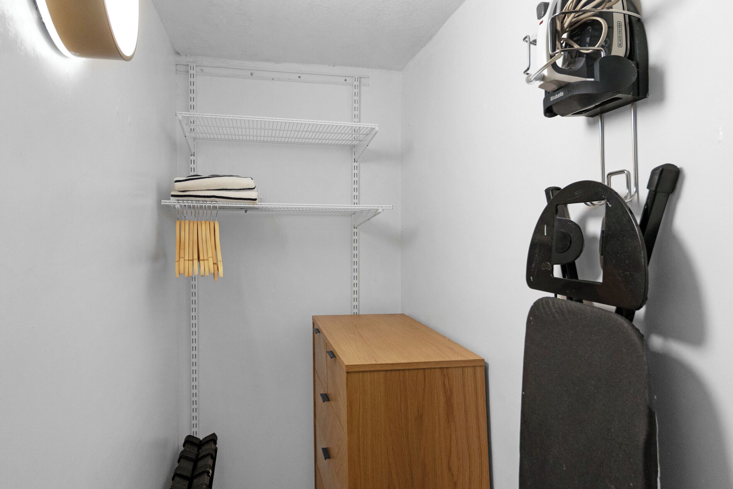 A compact storage area with metal shelves, a wooden cabinet, and a wall-mounted camera.