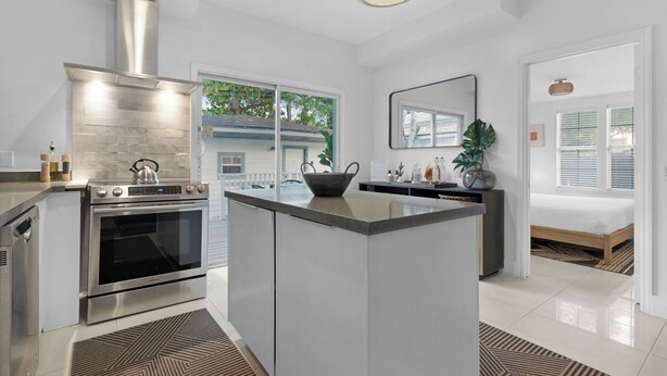 A modern kitchen with a large island, stainless steel appliances, and a view to the outside. - 7BD Downtown Oasis Pool  (Miami)