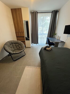 A modern hotel room with a bed, a chair, a desk, a television, and a view of the outdoors. - Private room in Colonia Roma Norte. (Ciudad de México)