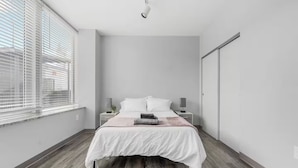 Une chambre moderne avec un lit, des tables de chevet et une fenêtre avec des stores.
