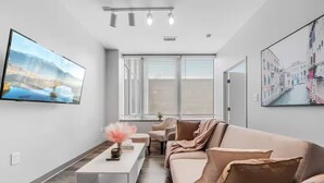 Un salon moderne avec un canapé, une table basse et un téléviseur fixé au mur.