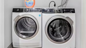 A laundry room with two front-loading washing machines and a Tide detergent bottle on the left. - DT · Fast Wifi · Pet Friendly · Bidet Sprayer (Cleveland)