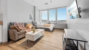 A modern living room with a sofa, a coffee table, and a TV mounted on the wall. - DT · Gym · Pet Friendly · 1 Bus to Clinic or CSU (Cleveland)