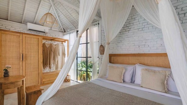 Un dormitorio con cama con dosel, armario de madera y vistas a la vegetación.