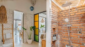 Un baño moderno con pared de ladrillo, ducha y lámpara colgante.