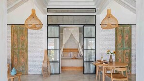 Una habitación con cama, una mesa de comedor con sillas y una lámpara colgante.