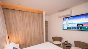 Ein Schlafzimmer mit einem Bett, einem an der Wand befestigten Fernseher und zwei Korbstühlen.