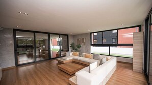 Ein geräumiges Wohnzimmer mit einer großen Eckcouch, einem Couchtisch und einer Glastür, die zu einem Außenbereich führt.