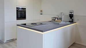 Eine moderne Küche mit Kochinsel, Einbauofen und Kaffeemaschine.